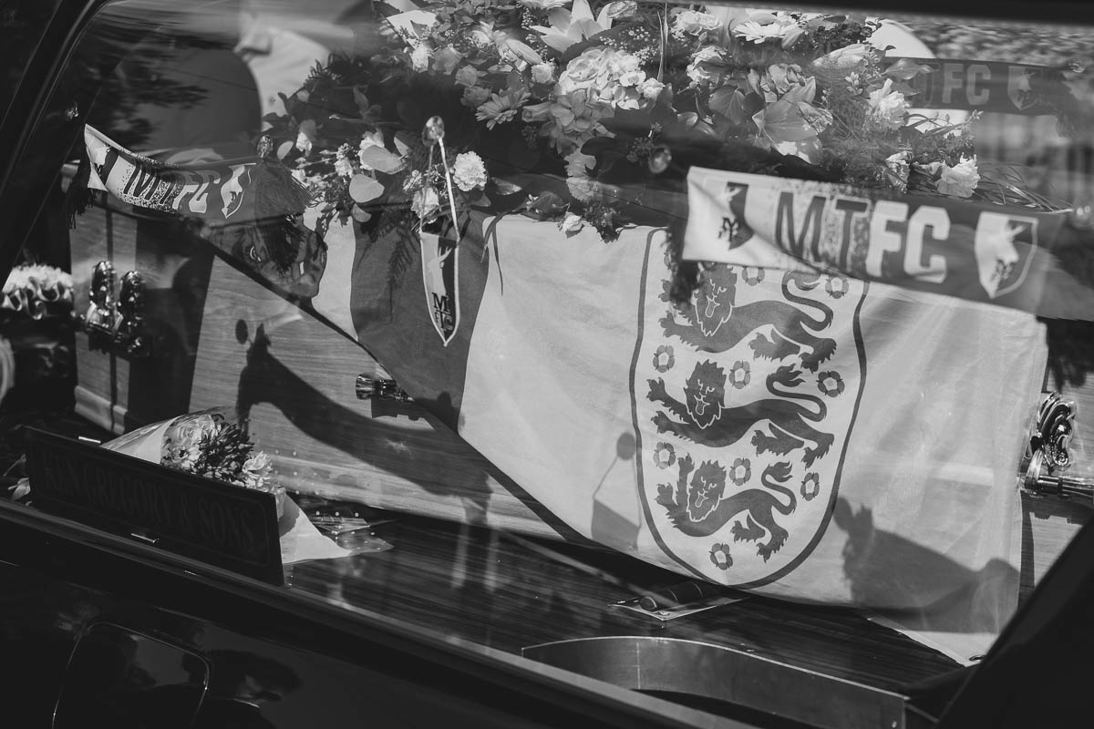 Hearse with coffin draped in flags and flowers